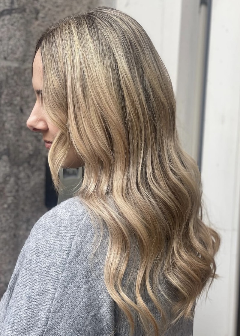 Naturligt blondt hår med bløde bølger og lyse striber, set fra siden
